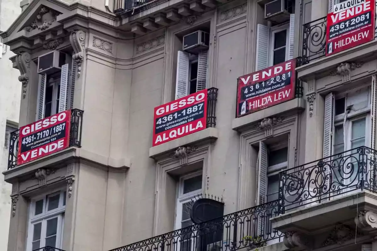 Fachada de un edificio con varios carteles de "Vende" y "Alquila" de diferentes inmobiliarias.