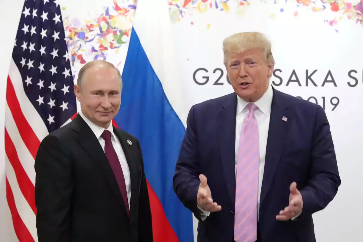 Dos personas de pie frente a banderas de Estados Unidos y Rusia en un evento del G20 en Osaka 2019.