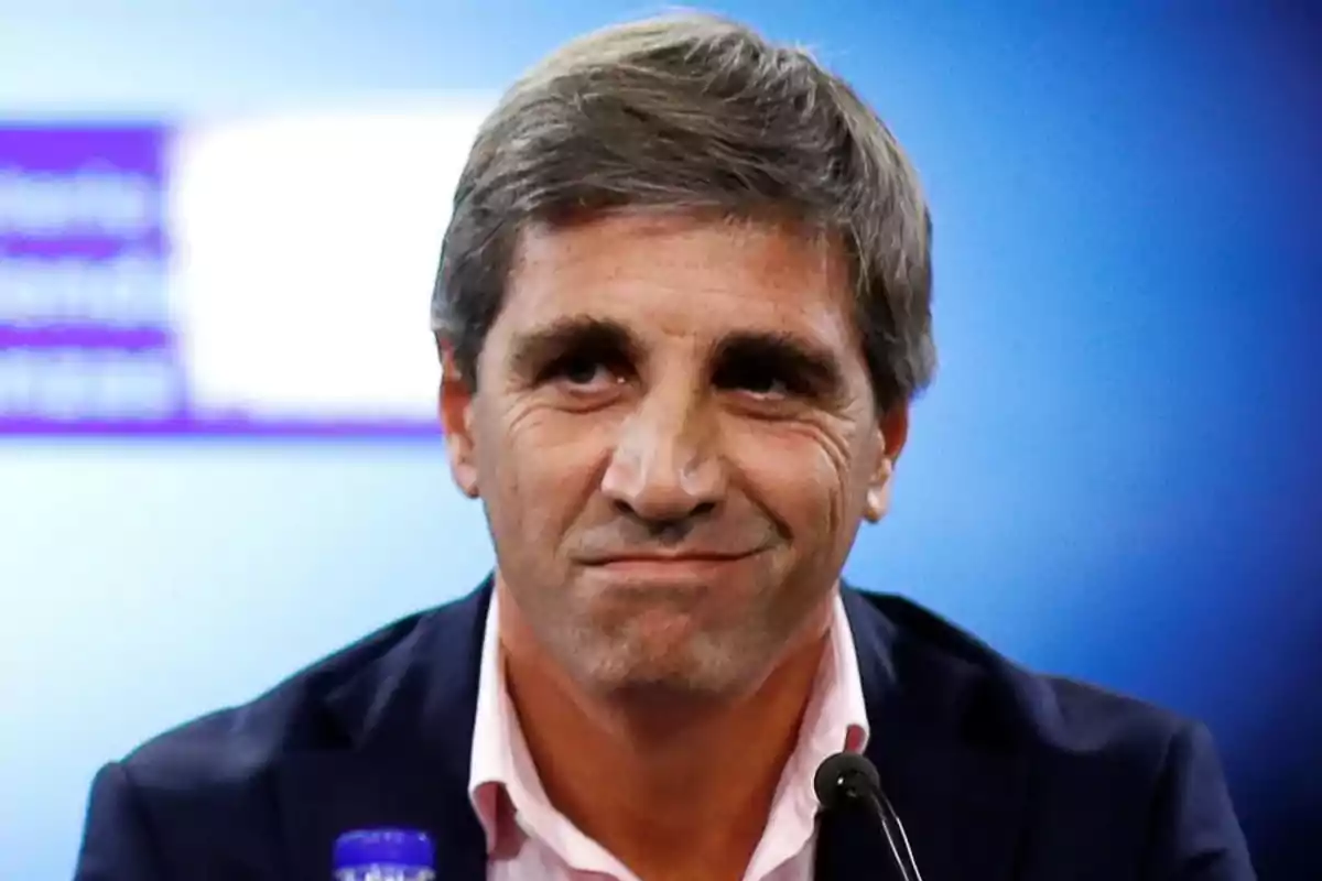 Un hombre de cabello canoso y expresión seria en un fondo azul.