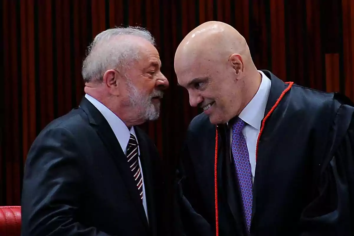 Dos hombres de traje conversando y sonriendo en un entorno formal.