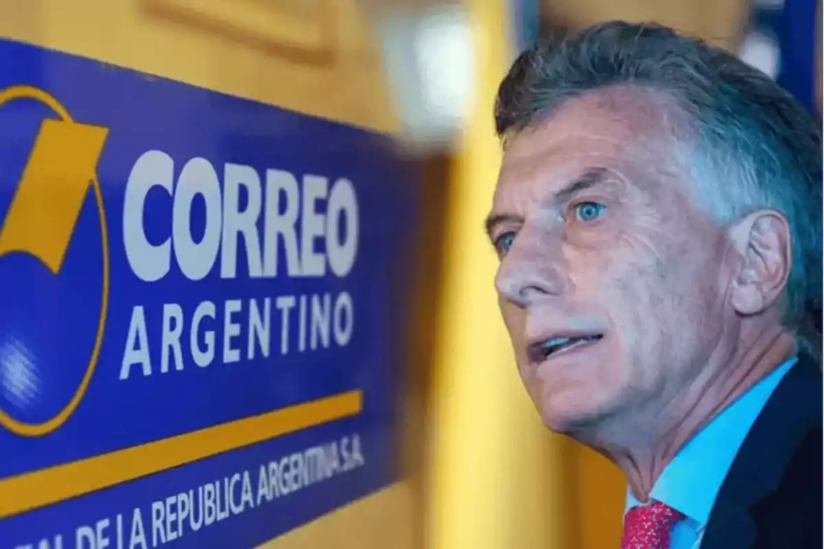 Hombre de traje junto a un cartel del Correo Argentino.