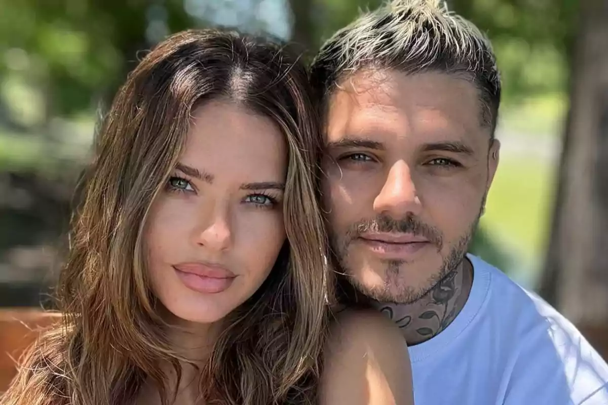 Una pareja posando al aire libre con árboles de fondo.