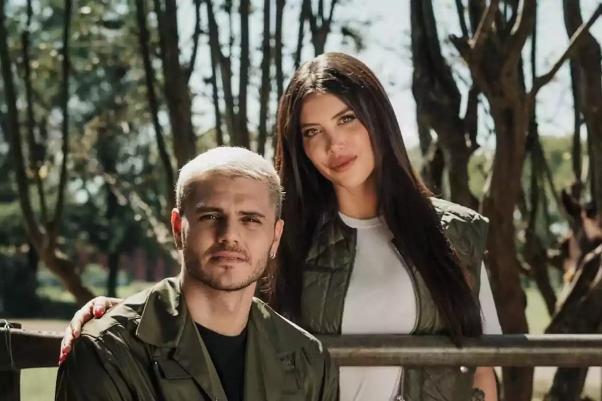 Una pareja posando al aire libre con árboles de fondo.