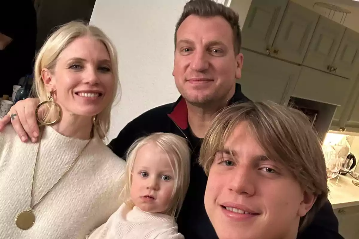 Una familia sonriente posa junta en una cocina.