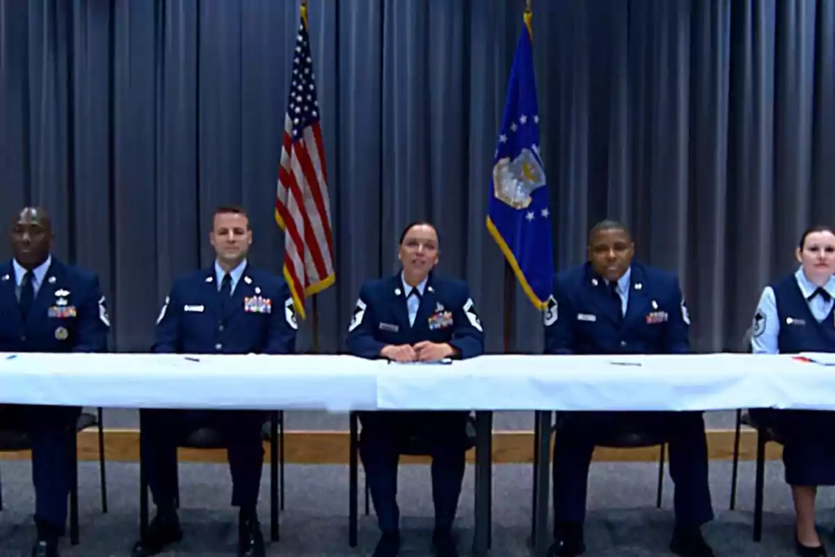 Cinco personas en uniforme militar están sentadas detrás de una mesa con banderas de Estados Unidos y de la Fuerza Aérea al fondo.