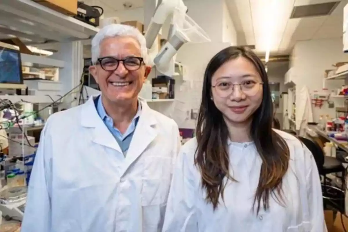 Dos personas con batas de laboratorio sonríen en un entorno de laboratorio.