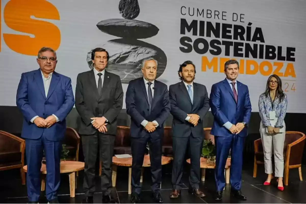 Un grupo de personas en traje formal posando en un escenario durante la Cumbre de Minería Sostenible en Mendoza.