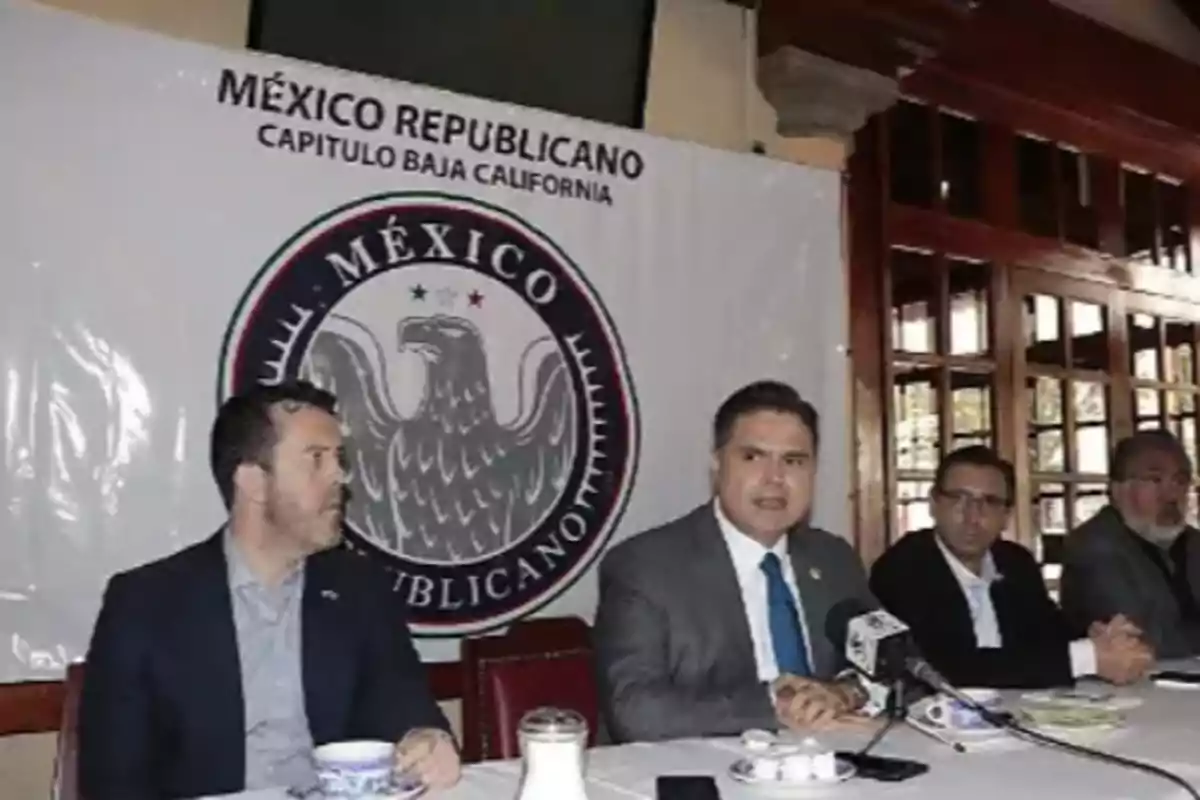 People sitting at a table during a press conference with a 