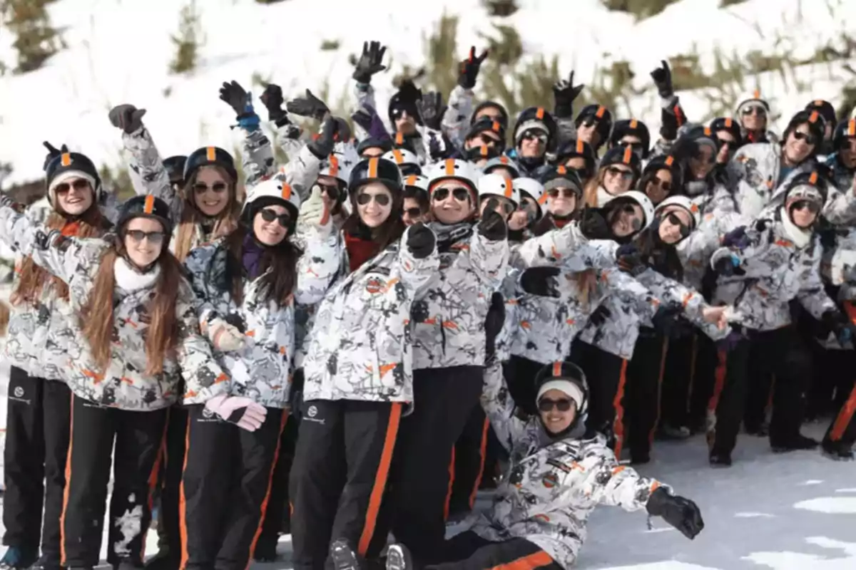 Un grupo de personas con ropa de invierno y cascos posando alegremente en la nieve.