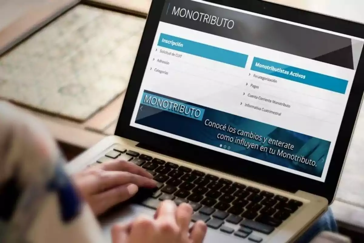 Persona usando una computadora portátil para consultar información sobre el monotributo en una página web.
