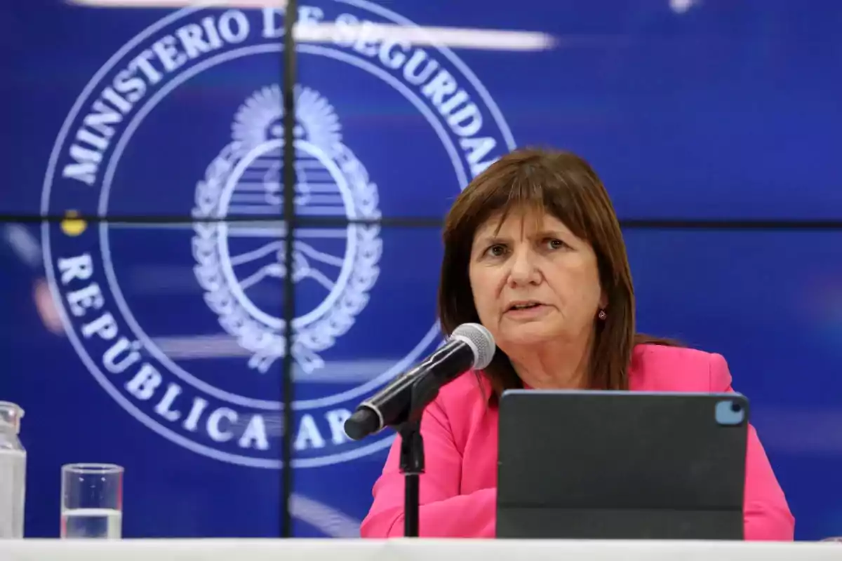 Una mujer hablando en una conferencia de prensa frente a un micrófono con el logo del Ministerio de Seguridad de la República Argentina en el fondo.