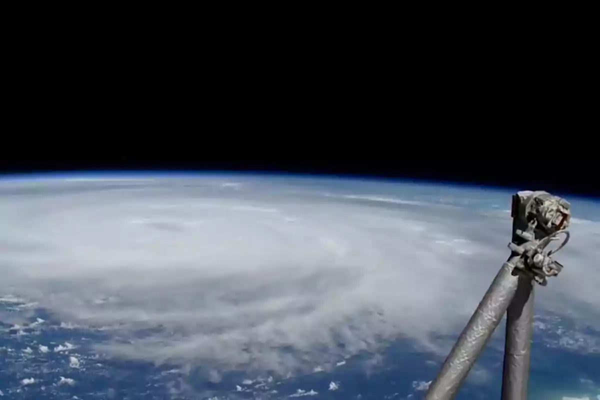 Vista de un huracán desde el espacio con parte de una estructura metálica en primer plano.