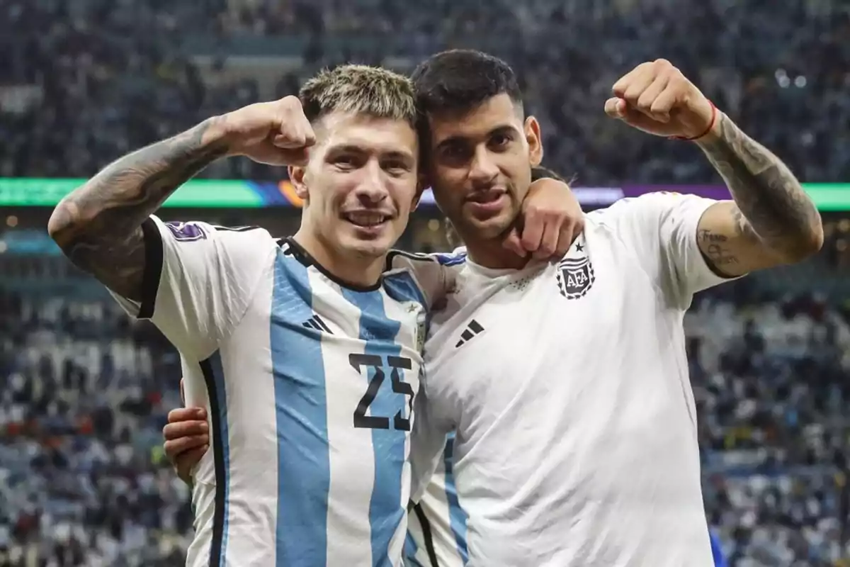 Dos jugadores de fútbol con camisetas de Argentina celebran juntos en el campo.