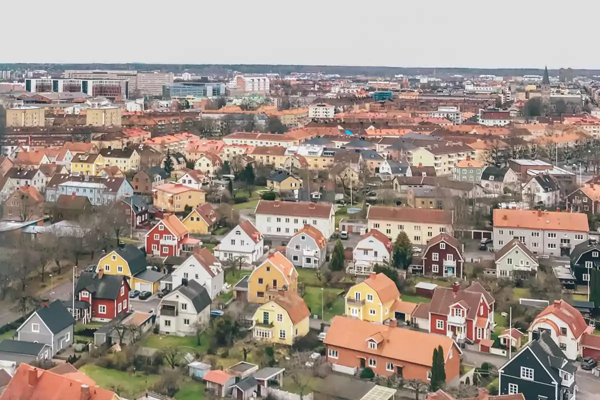 Vista aérea de un barrio residencial con casas de colores y edificios al fondo.