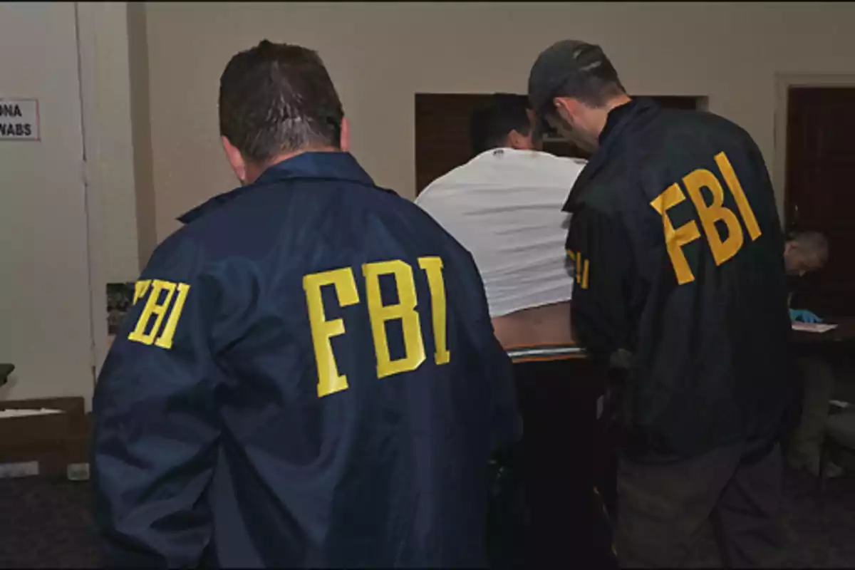 Agentes del FBI realizando una inspección a una persona en una habitación.