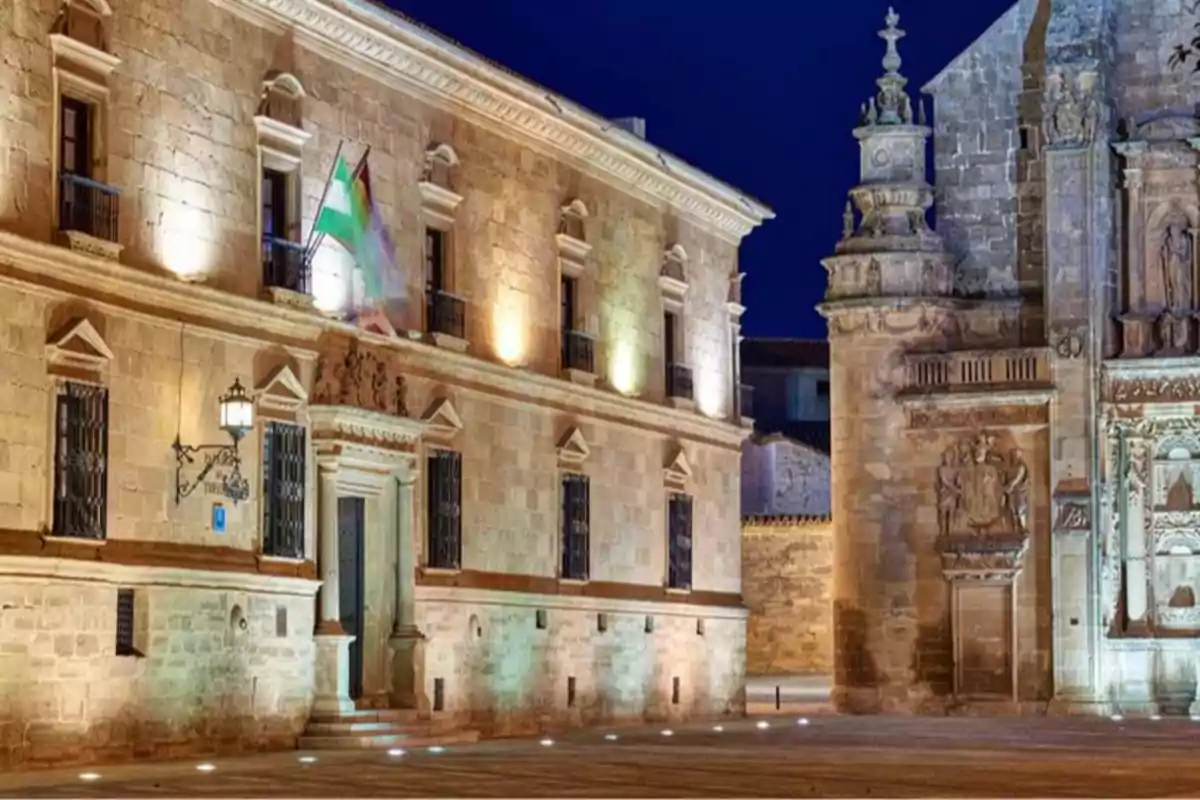 Edificio histórico en un pueblo de España iluminado por la noche con detalles arquitectónicos en piedra, donde ofrecen trabajo y vivienda gratis