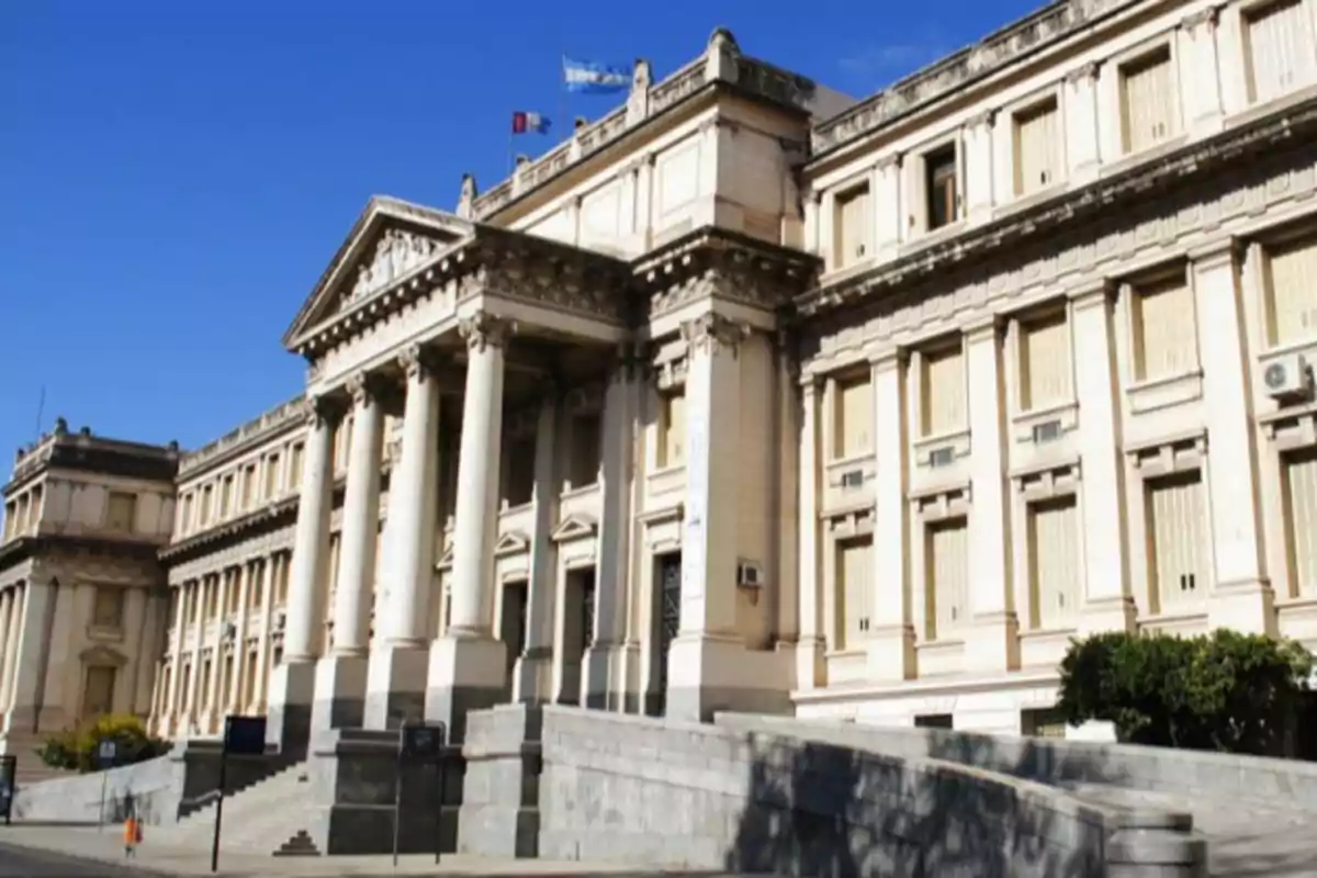 Edificio histórico con columnas clásicas y fachada imponente bajo un cielo azul.