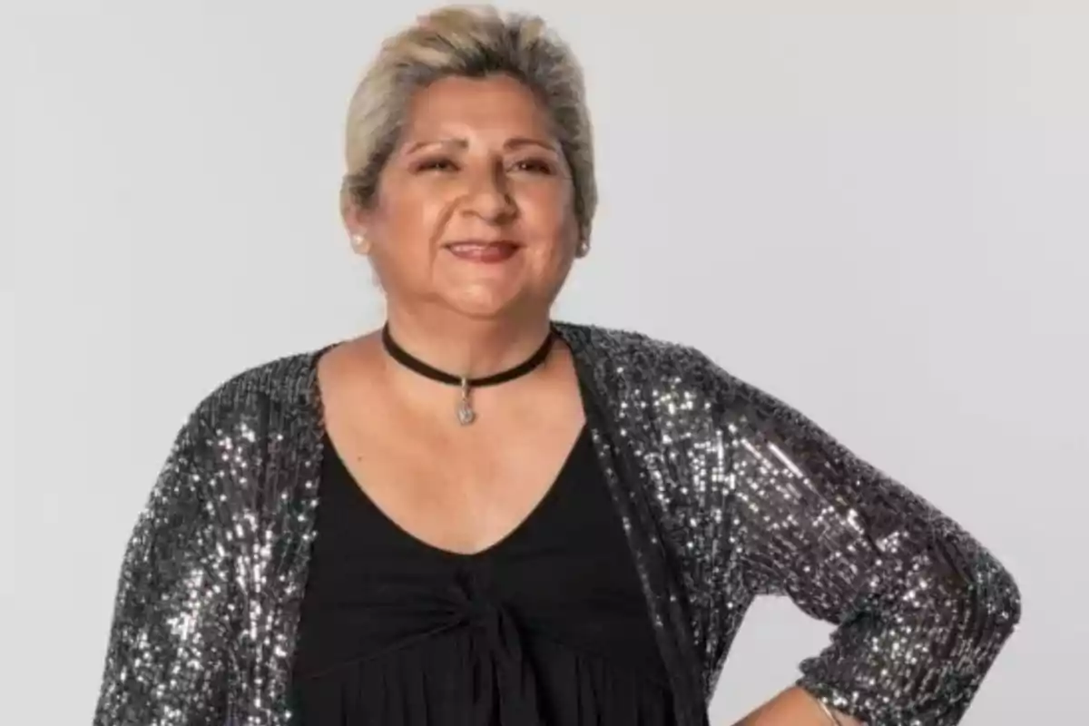 Mujer sonriendo con cabello rubio y un atuendo negro brillante.