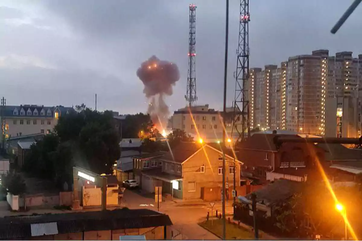 Una explosión en una zona urbana con edificios y torres de comunicación al atardecer.