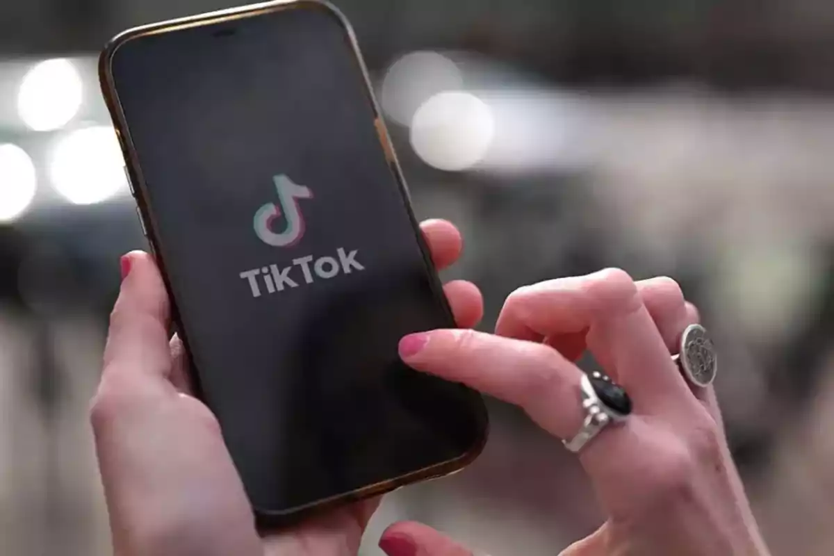 Persona sosteniendo un teléfono móvil con la aplicación TikTok abierta en la pantalla.