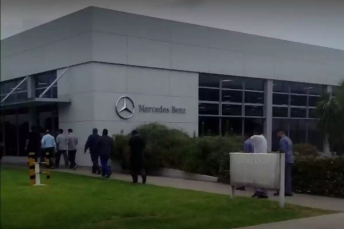 Edificio de Mercedes-Benz con personas caminando hacia la entrada.