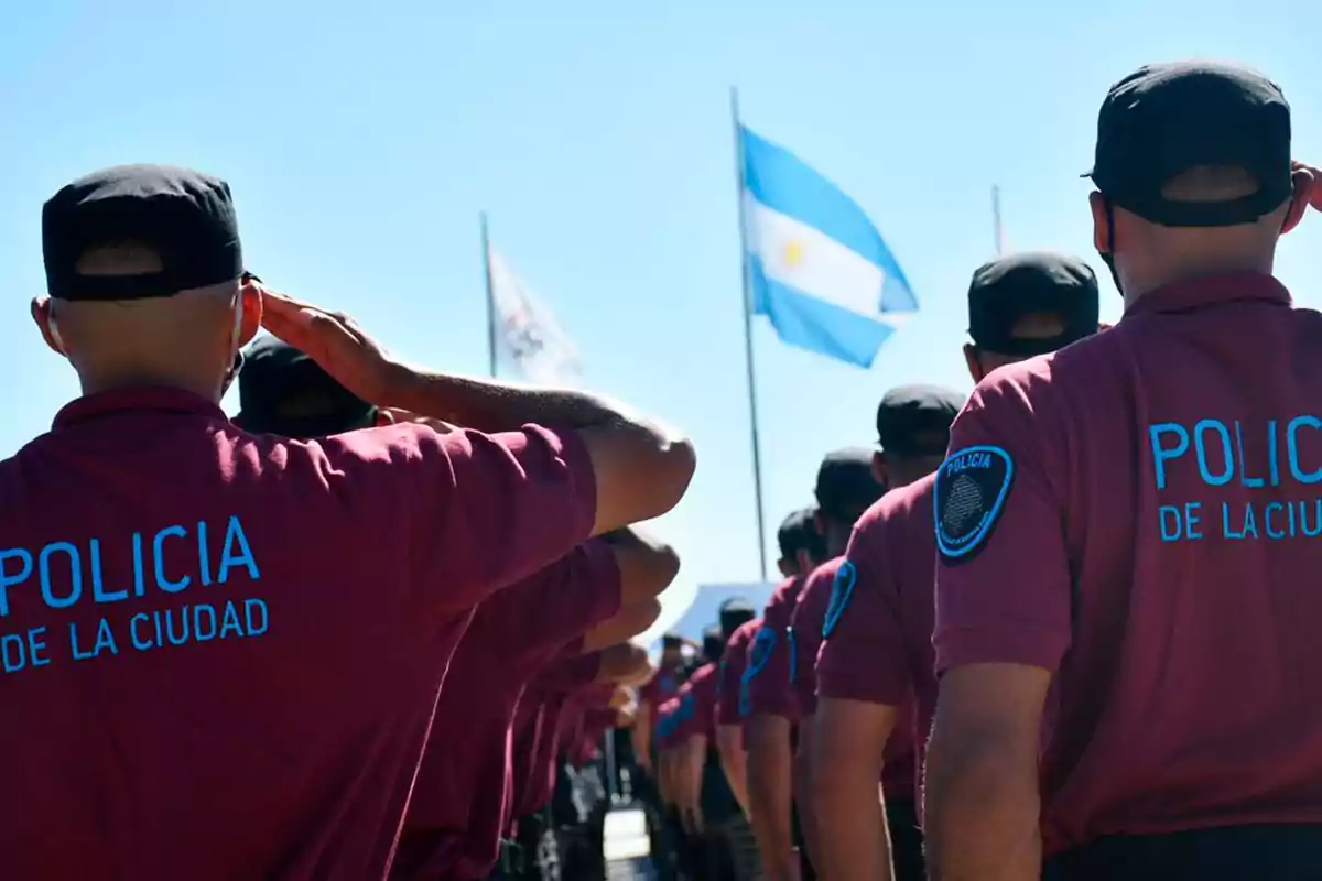 Policías de la ciudad en formación saludan a la bandera argentina.