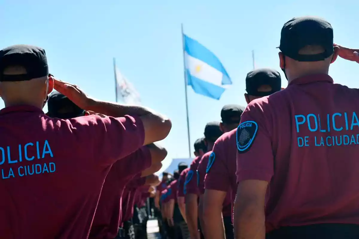 Policías de la ciudad saludan a la bandera argentina en una ceremonia al aire libre.