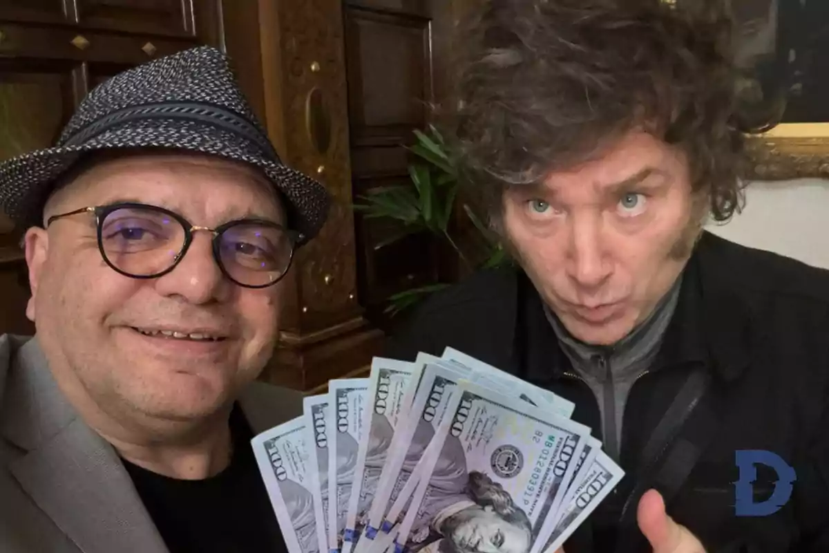 Dos personas posando juntas mientras una de ellas sostiene billetes de cien dólares.