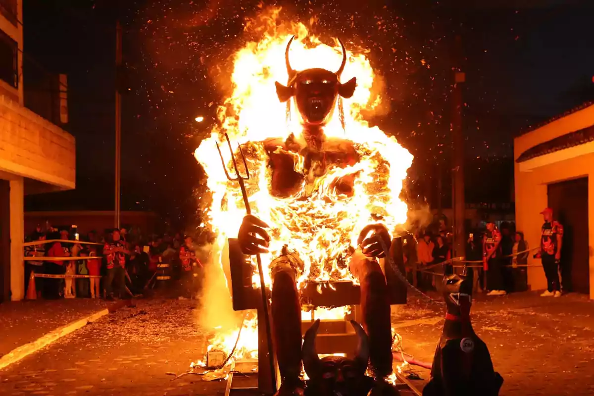 Figura de un diablo en llamas durante una celebración nocturna con espectadores alrededor. tradición navideña en Guatemala.