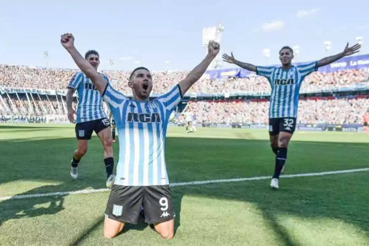 Jugadores de fútbol celebrando un gol en un estadio lleno de aficionados.