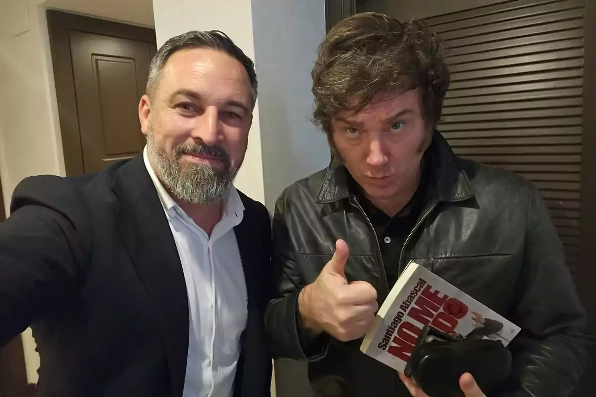 Dos hombres posan para una foto, uno de ellos sostiene un libro titulado "No me rindo" de Santiago Abascal.