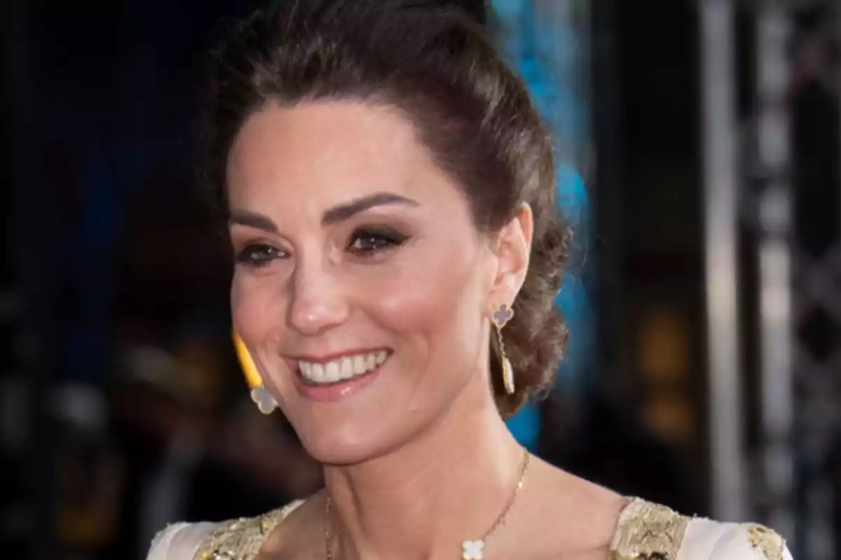 Una mujer sonriente con cabello recogido y aretes elegantes.