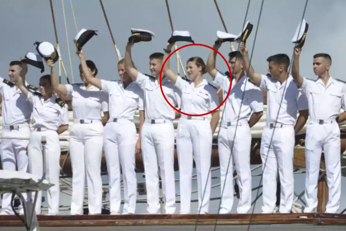 A group of people in white naval uniforms raising their caps on a ship.