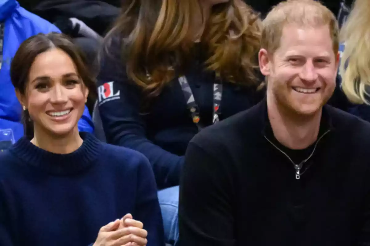 Dos personas sonrientes sentadas en un evento deportivo.