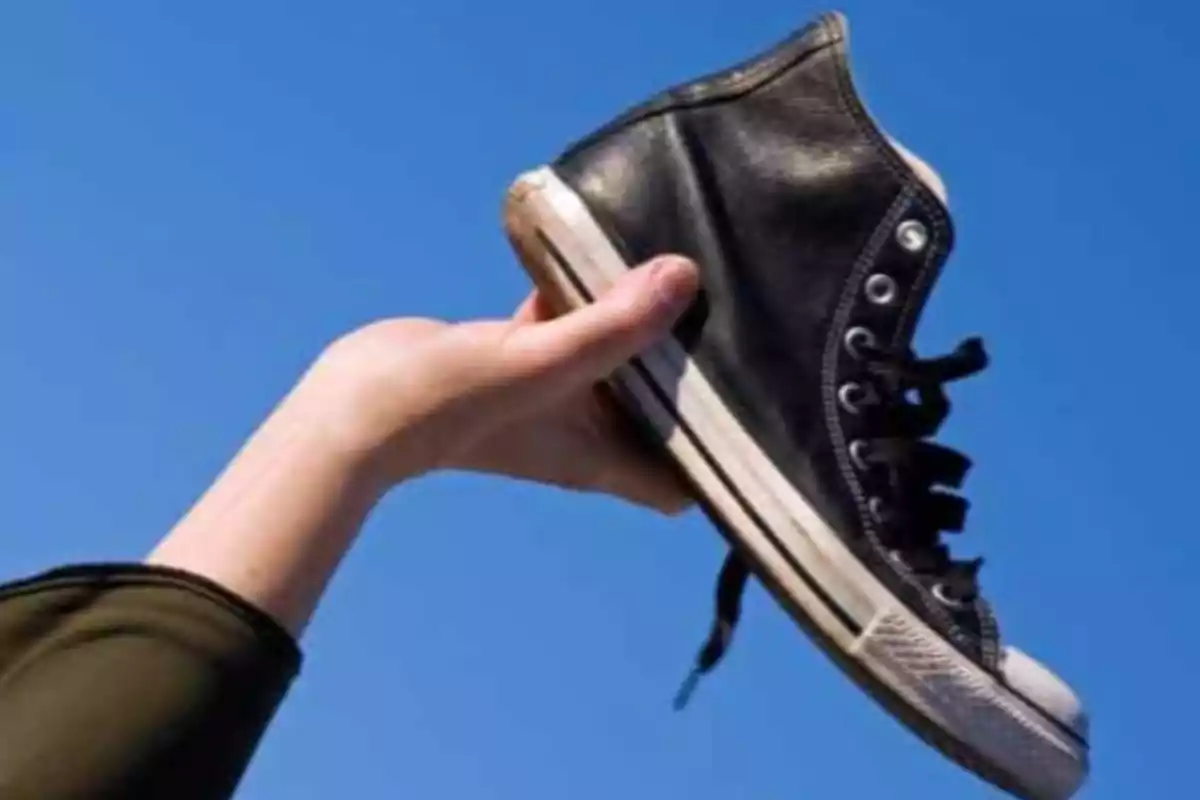 Una mano sosteniendo una zapatilla negra contra un cielo azul. tradición navideña en República Checa.