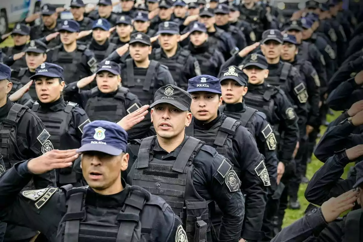 A group of uniformed police officers performs a military salute in formation.