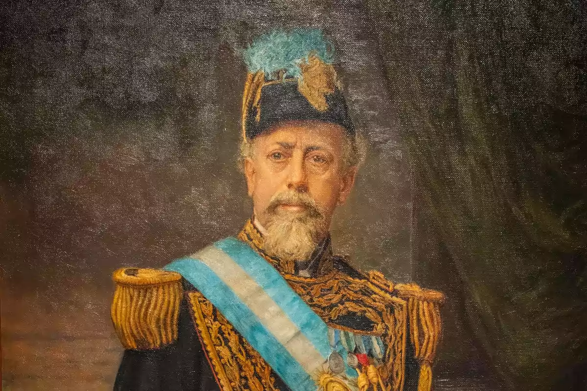 Retrato de un hombre con uniforme militar adornado con medallas y una banda azul y blanca.