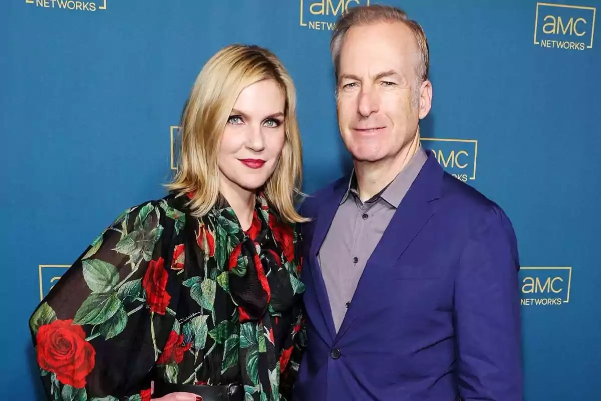 Rhea Seehorn y Bob Odenkirk posando juntas frente a un fondo azul con el logo de AMC Networks.