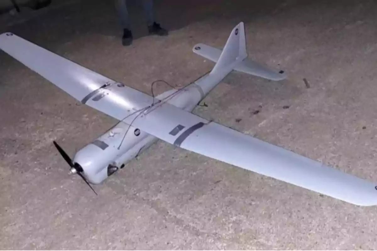 A fixed-wing drone on the ground with a propeller at the front.