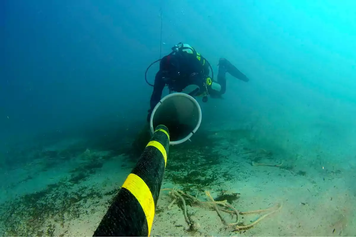 Buceador trabajando en la instalación de un cable submarino en el fondo del océano.