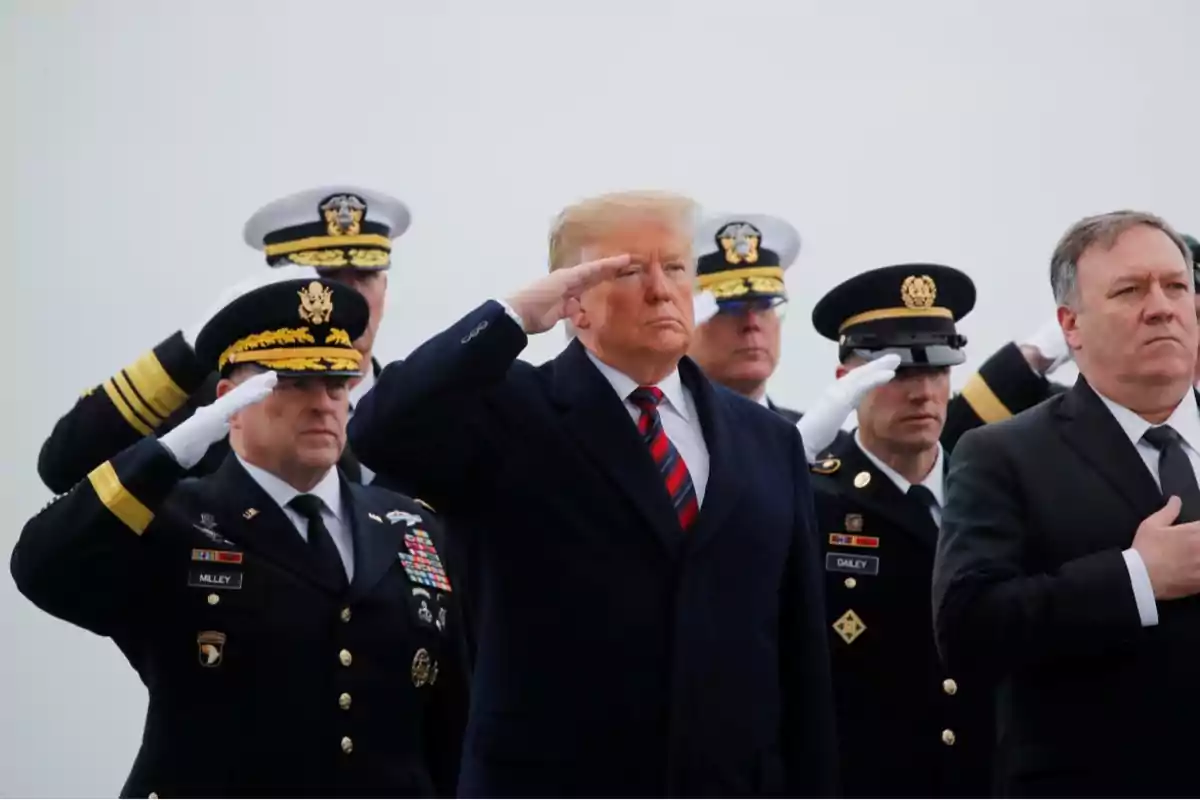 Un grupo de personas en uniforme militar y traje formal realizando un saludo.