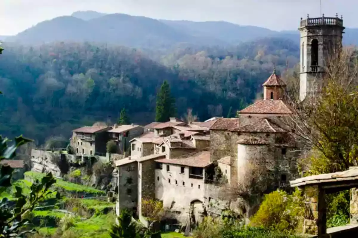 Vista panorámica de un pintoresco pueblo medieval rodeado de montañas y vegetación.