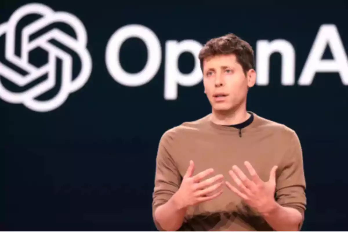 Persona hablando en un escenario con el logo de OpenAI de fondo.