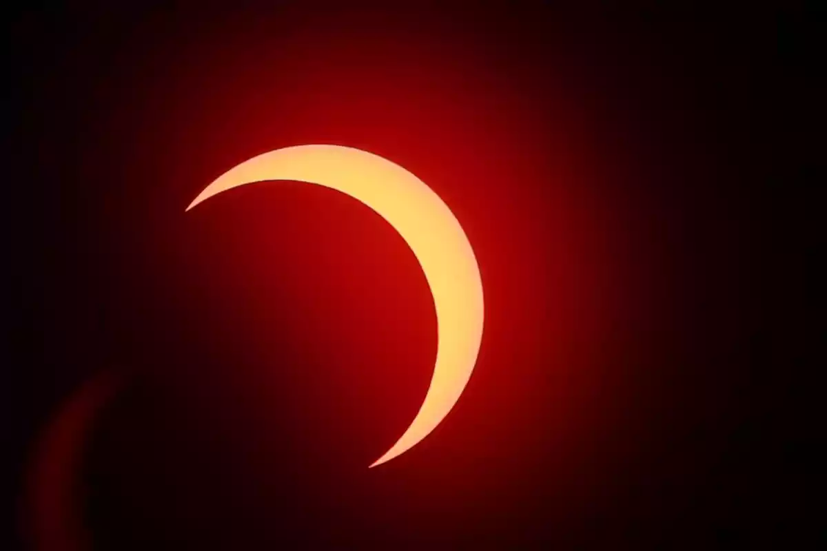 Eclipse solar parcial con fondo rojo.