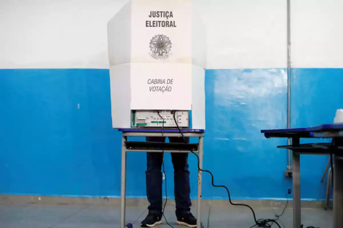 Persona votando en una cabina electoral con un fondo azul.