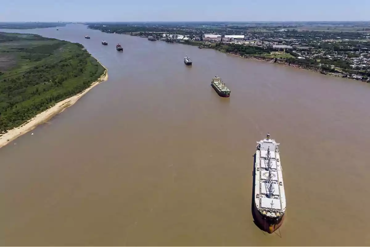 Vista aérea de un río con varios barcos navegando y vegetación en la orilla izquierda.