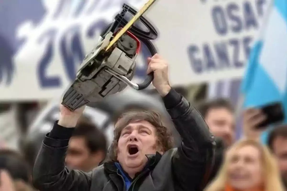 Una persona levantando una motosierra en un evento público con una bandera argentina de fondo.