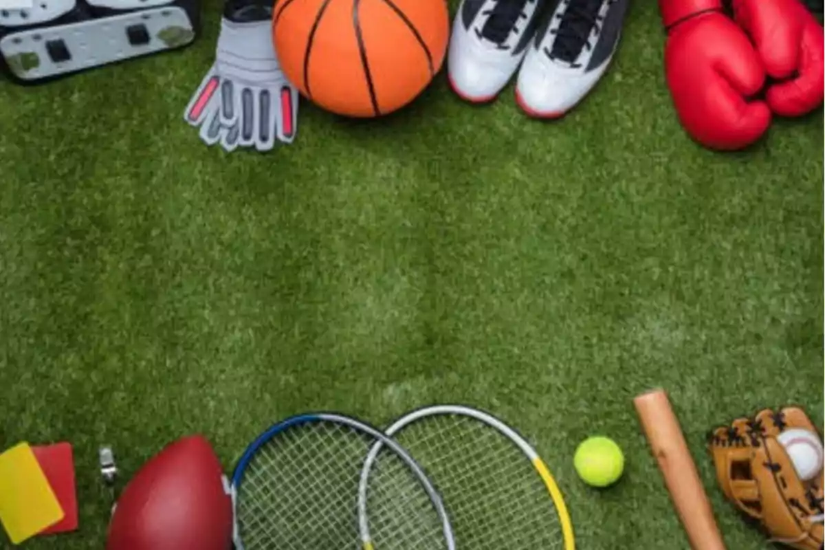 Equipamiento deportivo sobre césped incluyendo un balón de baloncesto guantes de boxeo raquetas de tenis y un guante de béisbol.