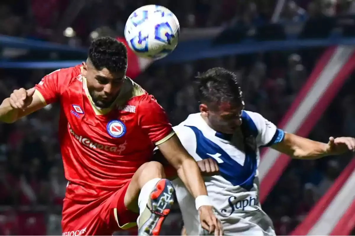 Dos jugadores de fútbol compiten por el balón en el aire durante un partido.