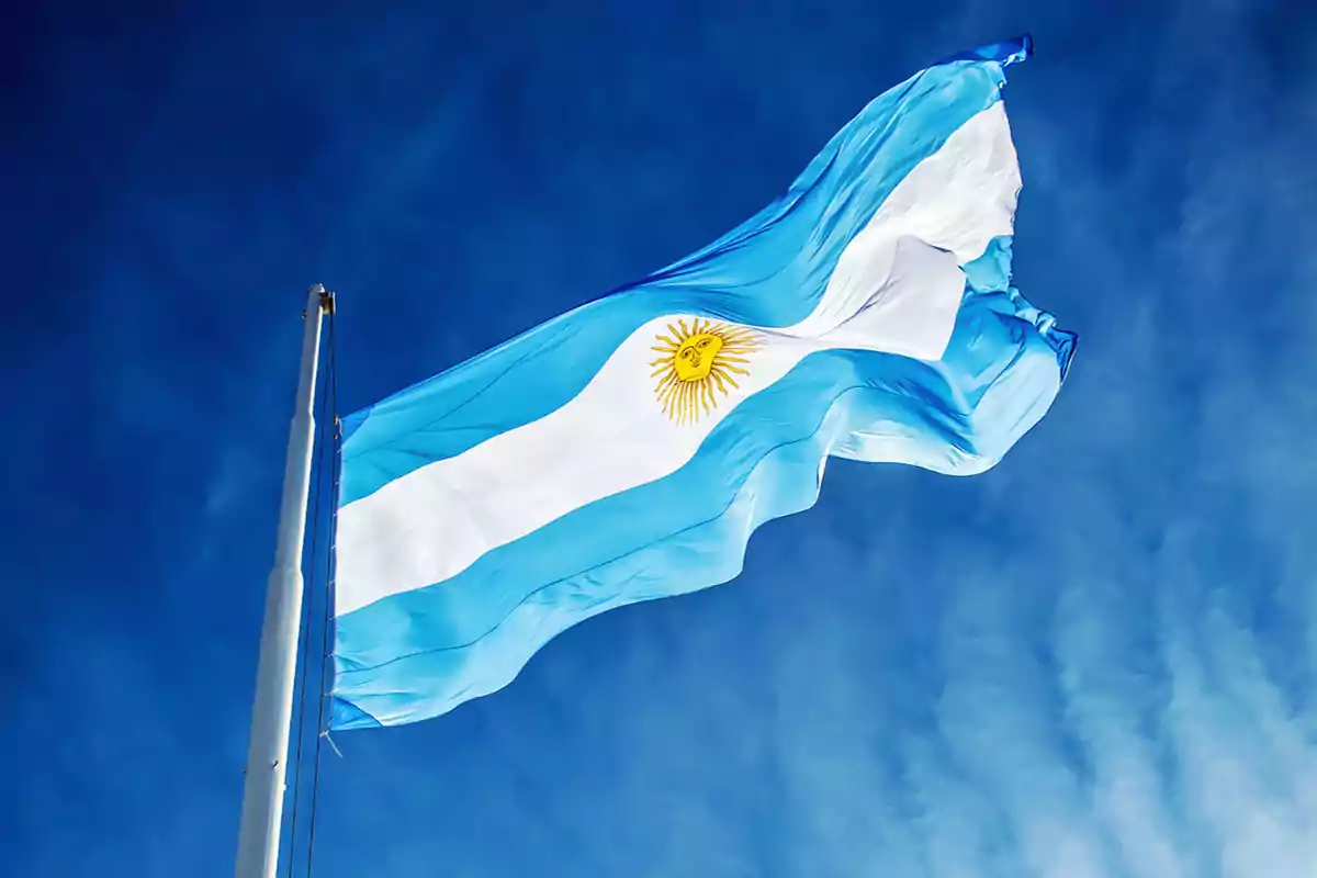 Bandera de Argentina ondeando en un cielo azul.